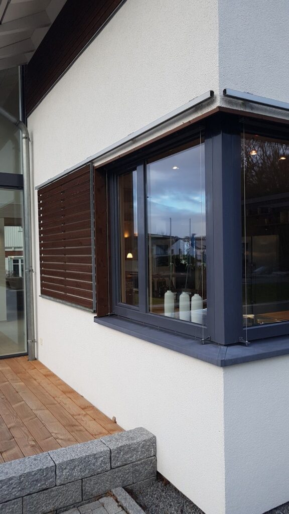 Modern house with sliding wooden shutters and dark frame windows