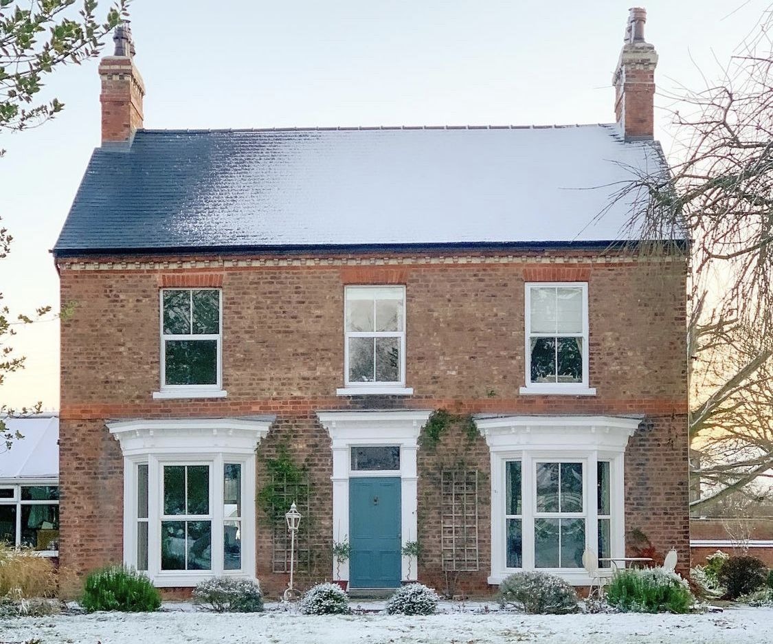 Brick two-story home with snow-covered roof in winter